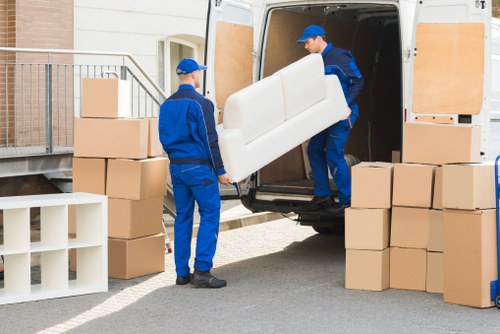 Professional movers transporting boxes and furniture through a Hampstead property