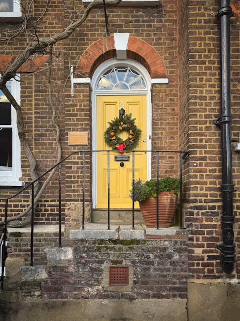 A close-up view of a brick wall displaying a metal house nameplate reading 'LOWER TERRACE NW3' attached to the exterior of a building. The background is blurred, showing greenery and trees, indicating an outdoor setting. This scene is part of a house relocation context, with the focus on the building's address sign that might be relevant during furniture transport or moving logistics for Hampstead homes, as handled by Man with Van Hampstead. The natural light highlights the texture of the bricks and the metal sign, emphasizing the structural elements involved in a typical move or packing process at a property in a narrow access area.